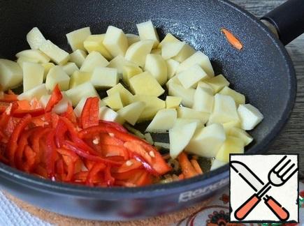 Add the potatoes and the straws of bell pepper, fry for 5 minutes, stirring, the heat is above average.
