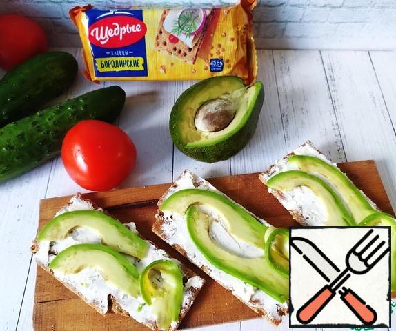 Peel the avocado, cut it into thin slices and place it on the loaves.