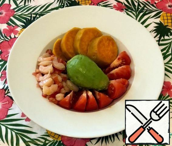 Peel the avocado from the peel and from the seed. Place it in the center of the plate. Next, place the slices of sliced tomato. Use half of the marinated shrimp with garlic for each serving. We put the plates of boiled sweet potatoes next to each other.