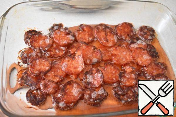 Preheat the oven to 150 g. Remove the skin from the sausage, cut it into thin rings and put it in a form greased with vegetable oil in 2 layers. Place in the oven and dry for 35-40 minutes.