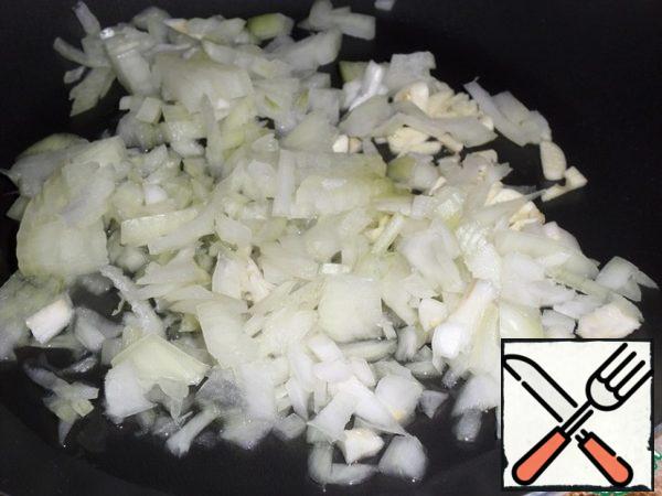 In a preheated frying pan, pour vegetable oil. Spread the chopped onion and garlic. Fry until golden brown over medium heat.