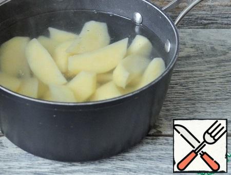 Turn on the oven to warm up.
Wash the potatoes, peel them, and cut them into large slices. Pour boiling water for 5 minutes, cover.