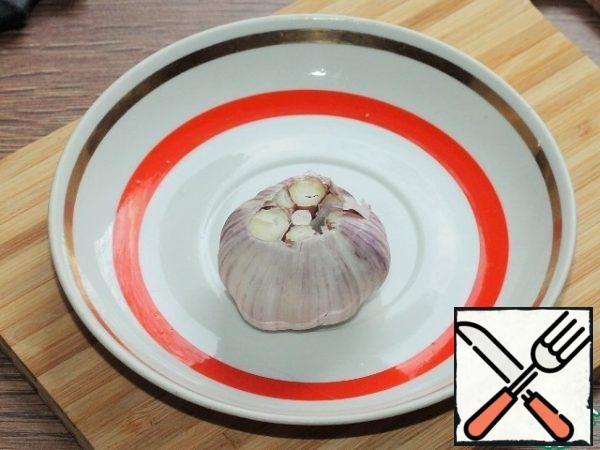 At the heads of garlic, without peeling the husks, we cut off a small part of the top, so that the slices become visible. Wrap the garlic in foil and send it to the oven, heated to 200 degrees, for 30 minutes.