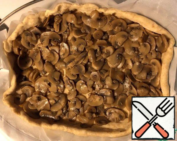 Carefully lay out a layer of mushrooms, so as not to squeeze the raised dough. If desired, you can pre-mix the mushrooms with dried onions and add salt to taste.