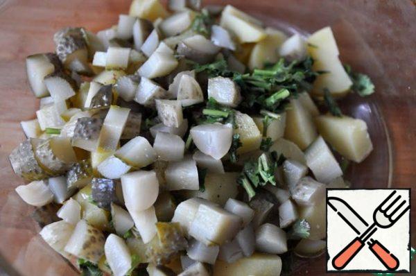 Add diced pickled gherkins and finely chopped coriander greens to the potatoes.
