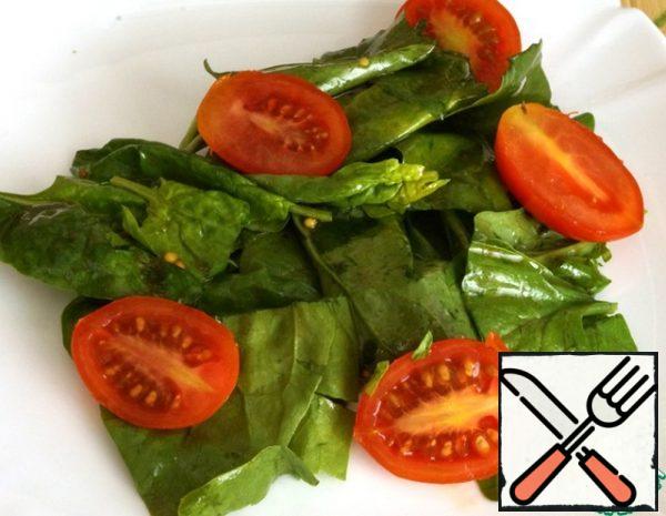 We begin to collect the salad. Put the seasoned spinach leaves on a plate, add the cherry tomatoes, cut in half.