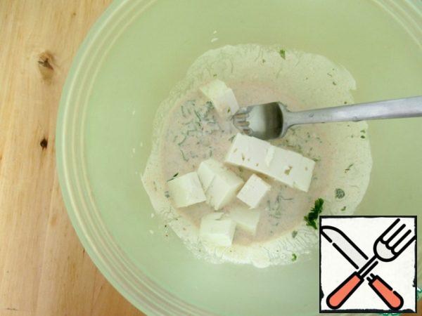 Add feta (100 g) to the dressing and mash it with a fork.