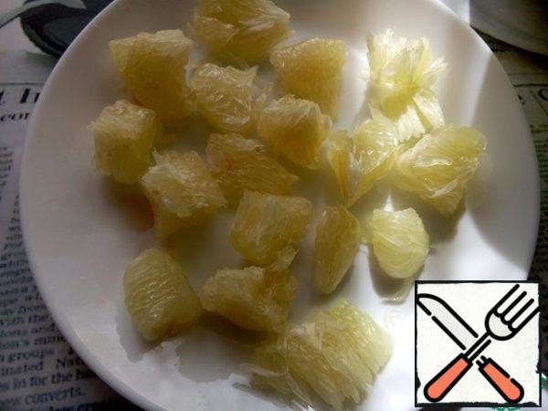 Clean the pomelo from the peel and films and disassemble it into small segments.