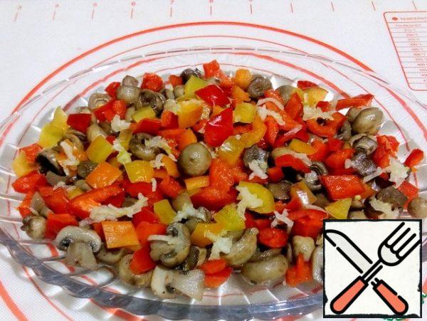 The first layer on the dish is laid with pickled mushrooms, diced Bulgarian pepper and crushed garlic.