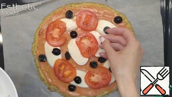When the base is baked, we take it out of the oven, lubricate the sauce, spread the cheese, tomatoes and olives on top of it. We send it to bake until the cheese melts. We get a ready-made pizza. It is possible to decorate with basil