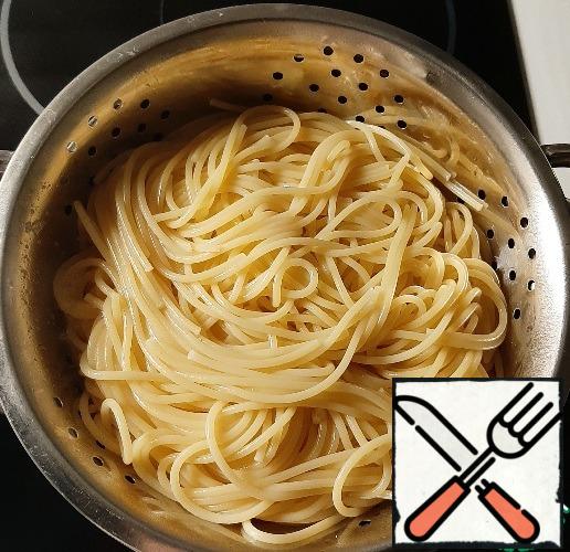 Boil the spaghetti in salted water, toss in a colander, return to the pan, pour over the olive oil, and mix.