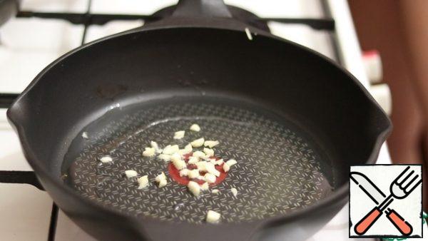In a preheated frying pan, greased with vegetable oil, fry the garlic.