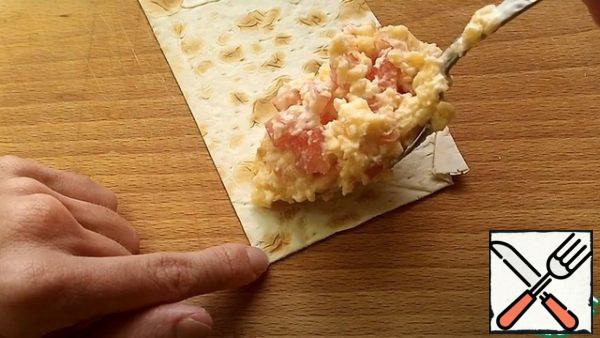 On the corner of the pita bread, put 1 tbsp.  of the filling and wrap it in an envelope.