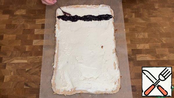 Turn the finished meringue over. Remove the parchment and allow to cool. Apply the cream to the cake. You can leave a little bit for decoration. Slightly retreating from the edge, make a strip of jam.
