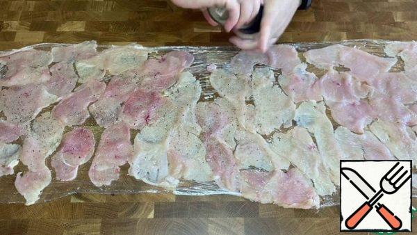 Remove the top film. Season each piece with salt and pepper.
