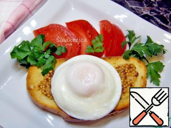 Serve the finished poached egg on toasted bread. It turned out to be round and neat, but I also cut the edges with a round notch so that the egg would fit nicely on the toast. You don't have to do that. I like to smear the toast with Dijon mustard, and you can serve it to your taste.