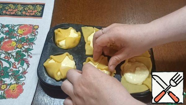 Evenly distribute the curd cream. Gently lift the edges of the dough and cover the filling. At the same time, you do not need to press hard.