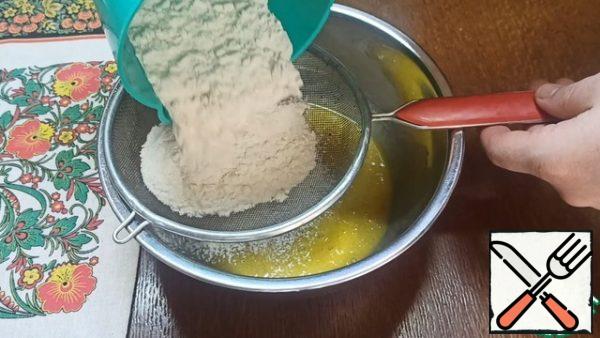 In the resulting mass, sift 180 g of wheat flour.