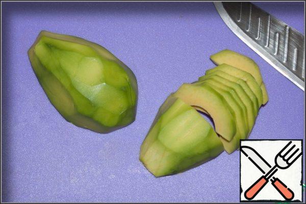 Peel the avocado, cut it in half, removing the stone, and cut it into slices.