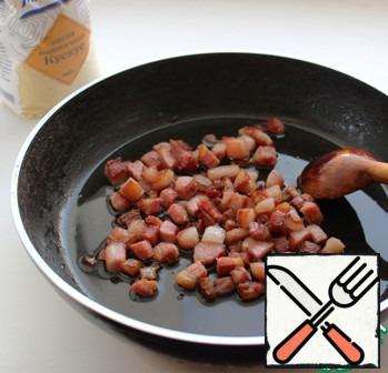 Heat 1 tablespoon of oil in a frying pan and fry the bacon in it until golden brown. Transfer the finished bacon to a heated plate.