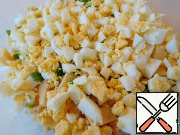 Crumble the eggs with a small cube.
We open the boiled rice, send it to the salad and mix it quickly.
You can lightly sprinkle everything with olive oil.