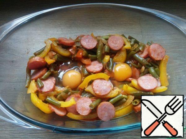 We transfer the vegetables prepared in this way to a heat-resistant dish, make small depressions and drive the eggs there. Bake in a preheated 180 degree oven for 15 minutes.