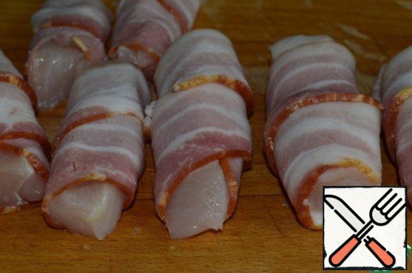 Cut the chicken fillet into strips (cubes) ~ 10 cm long. Then wrap a strip of bacon around each piece of chicken and put everything on a baking sheet.