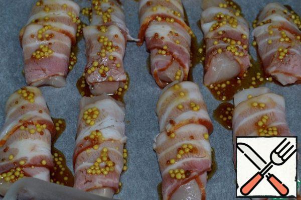 Using a brush, liberally lubricate the icing wrapped in bacon chicken fillet, put it in the oven, heated to 200 degrees, and bake for 8-10 minutes, until golden brown.
Then turn the pieces of meat, smear with icing, return to the oven for another ~ 5-7 minutes until browned.