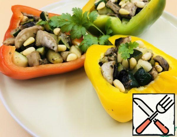 Cut the peppers in half, remove the seeds. Place on a baking sheet, cut down, and bake in the oven at 180 C for 10 minutes. Meanwhile, prepare the filling: in a dry pan, lightly fry the pine nuts, remove. 
