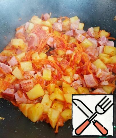 Chop the onion and carrot, grate the tomato on a coarse grater, or cut into cubes, cut the potatoes and ham into cubes. In a frying pan with a thick bottom on a small amount of vegetable oil, pass the onion, carrot, potato, tomato and casserole (ham). Stir and cook for about 2-5 minutes.