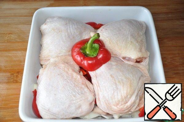 Chicken thighs are washed, dried. We take a convenient baking dish, put the onion and pepper down, on top of the thighs.
