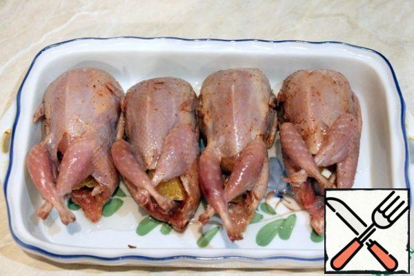 Rub the quail with salt and adzhika. Cut the tangerine and garlic and fill the quail, leave to marinate for 2 hours.