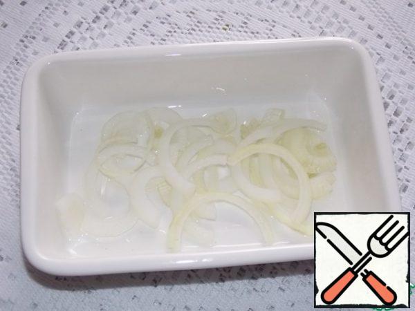 Grease the baking dish with vegetable oil, spread the onion, cut into half rings.