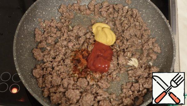 When the minced meat is already fried, add ketchup, mustard, garlic, chili pepper, and Worcestershire sauce, simmer for a couple of minutes and remove from the stove
