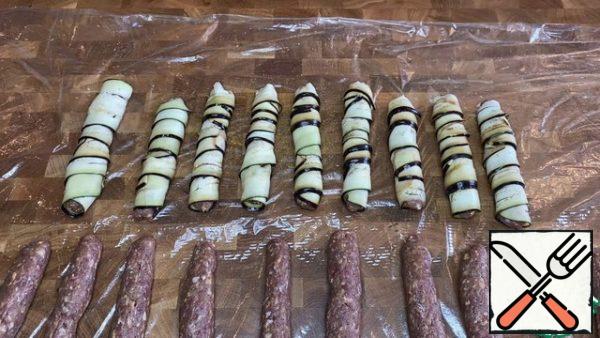 Part of the sausages (9 pcs.) wrap with eggplant plates. Wrap part of the sausages (9 pieces) in bacon.