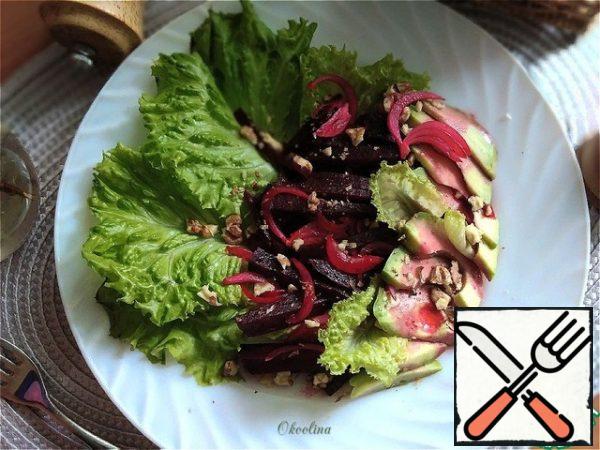 I will serve the salad to everyone individually. Put the salad leaves on a plate. On top of them, we put pickled beets with onions. Cut the avocado into slices and put it nicely on a plate. Pour the remaining beetroot dressing with onions and sprinkle with chopped walnuts.