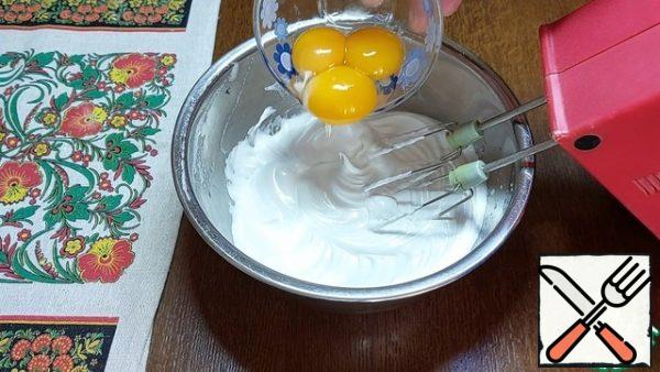 In the whipped whites, we mix the yolks one by one. We also send 10 g of vegetable oil there.
