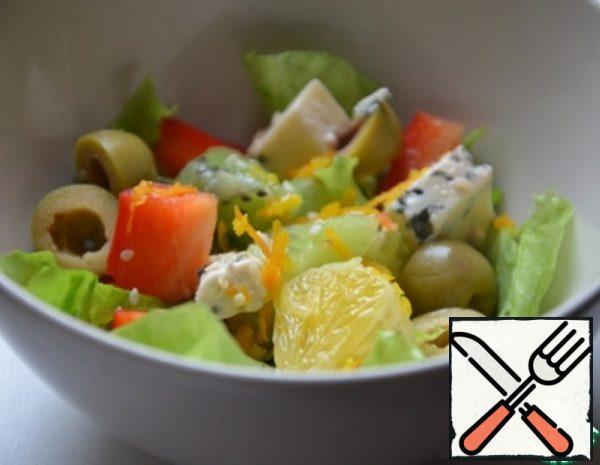 Cut the cheese and peeled pepper into cubes. Cut the olives in half.
Put the ingredients in a salad bowl, season with salt and pepper, sprinkle with sesame seeds and orange zest, and sprinkle with balsamic vinegar.