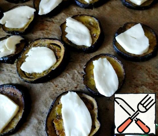Thinly slice the mozzarella.
Remove the baking sheet and put the cheese on the eggplant.
Bake until the cheese melts and gets a little golden.