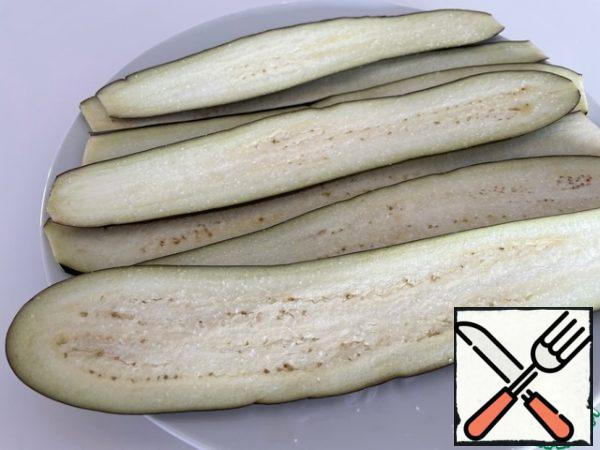 We use elongated eggplants. Cut into thin plates along the entire length, salt and leave for 5 minutes.