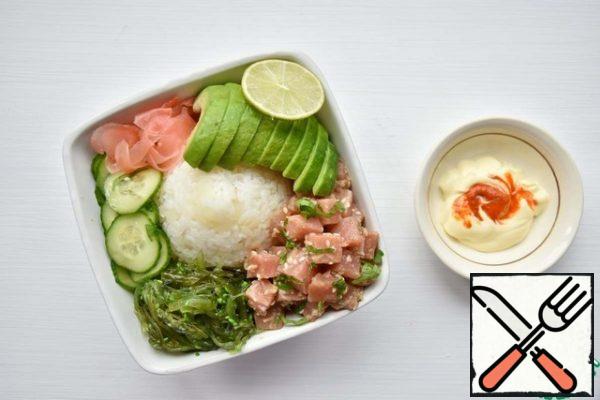 Place a pile of rice in the center of the plate. Place additional ingredients closer to the edges of the plate: cucumber slices (radish), pickled ginger, avocado, chuka seaweed, fish. Mix the mayonnaise with the sriracha sauce and add it over the rice. Sprinkle the dish with sesame seeds.

