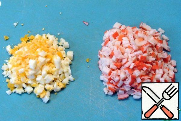 For the filling, boil the eggs, peel, cool. Finely chop. Cut the crab sticks into cubes.