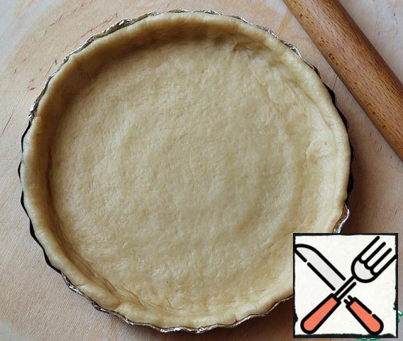 Roll out most of the dough into a circle and place it in a baking dish (diameter 28 cm). Cover the form with foil or baking paper and grease with vegetable oil (1 tsp).