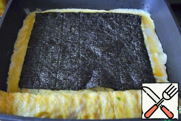 Pour in another ladle of the mixture, put the nori.