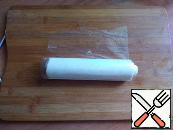 The dough has defrosted. Roll the puff pastry into a tight roll.