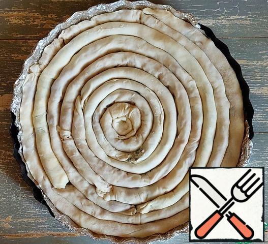 Cover the baking dish (diameter 28 cm) with foil, grease with vegetable oil (1/2 tbsp. l). Spread out the resulting rolls in the form of a spiral, in the order of alternating fillings.