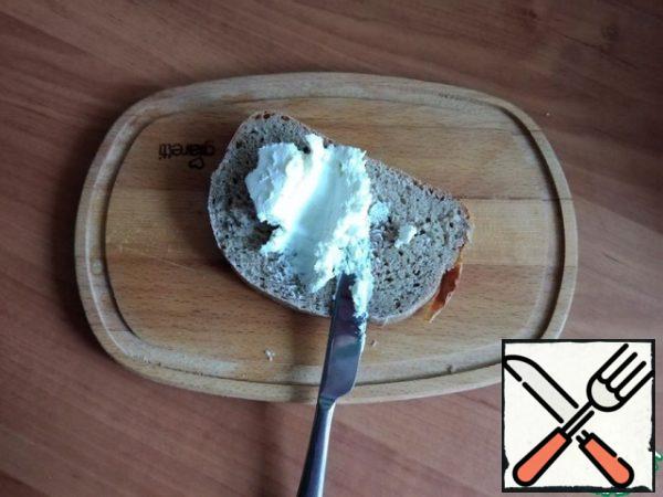 For serving, I will use a thick wooden board. We begin to collect Smerrebred. A thick layer of cottage cheese cream cheese is also spread on a thick piece of rye bread.