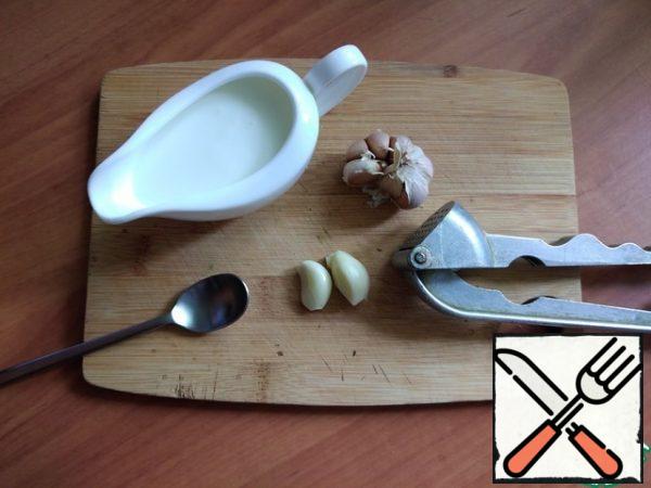 We make the sauce. Pour the yogurt into a bowl and squeeze out the garlic there. You can chop it finely.