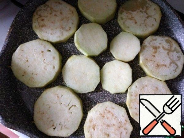 Pour the oil into a frying pan and heat it, spread the eggplant slices. I have the whole eggplant in a frying pan D-24 cm. Fry on one side.