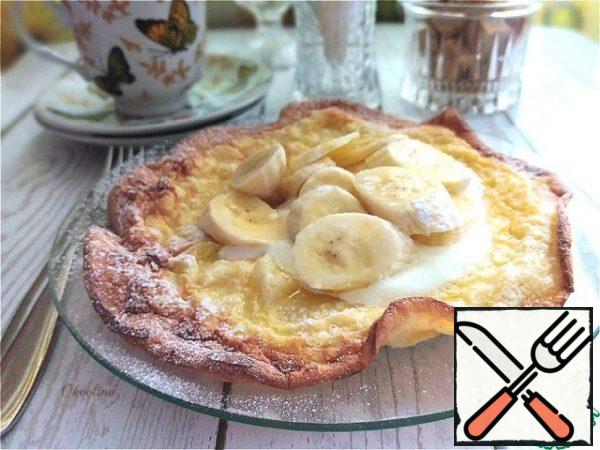We transfer it to a plate if desired. I'll put sour cream and a chopped banana on the pancake. I'll sprinkle everything on top with powdered sugar. Eat with whatever you want!